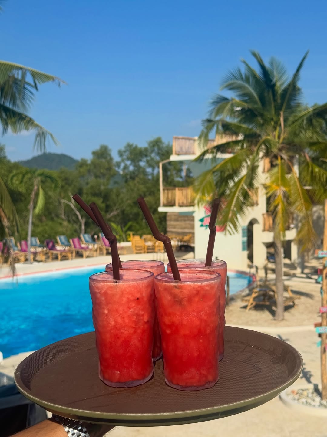 Watermelon cocktails on a tray at Jump Shack with the pool and diving tower behind
