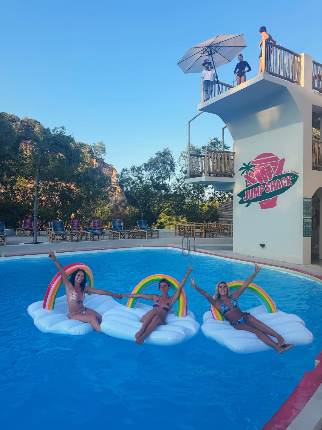 Guests on rainbow floaties in the Jump Shack pool during a pool party